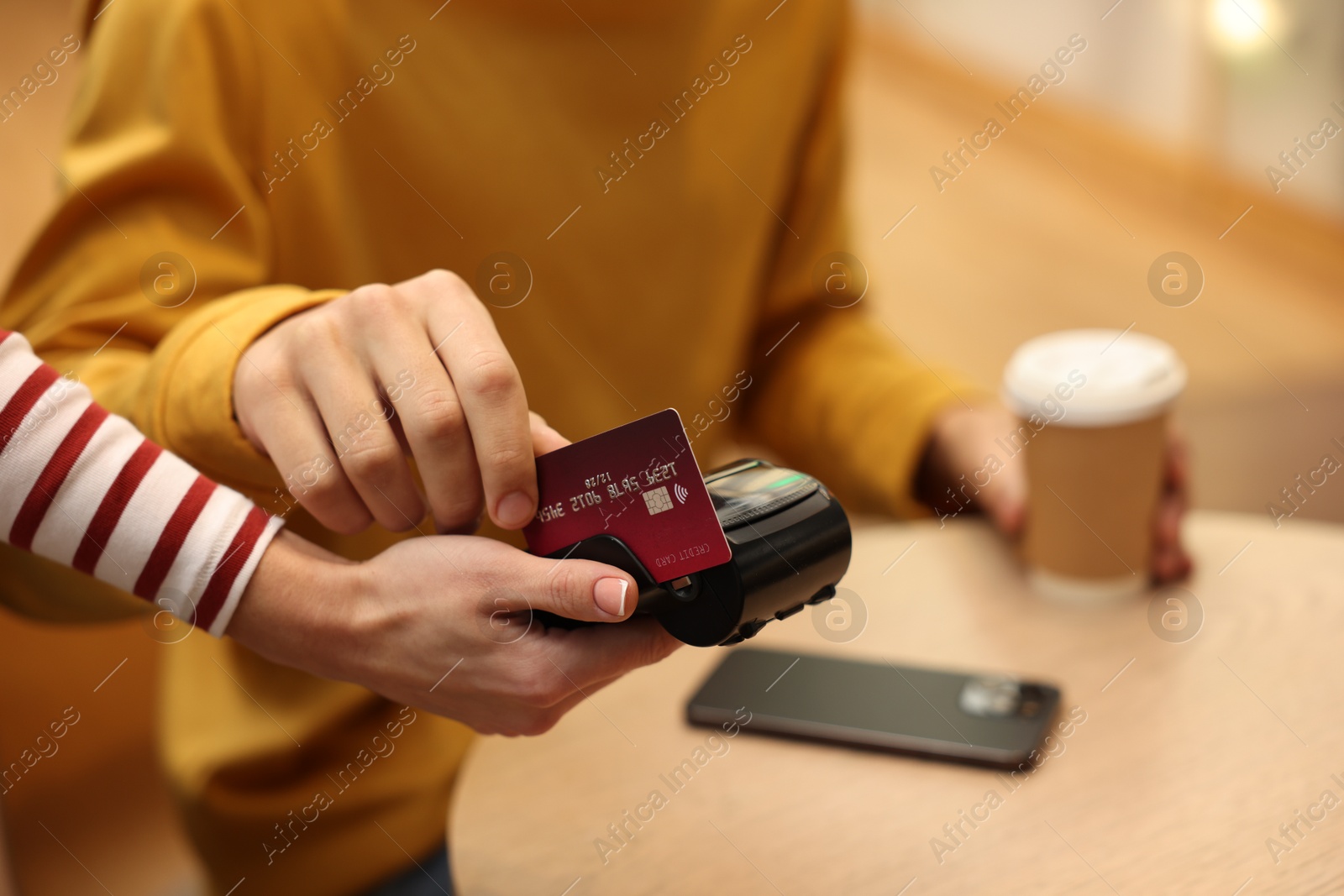 Photo of Man paying with credit card via terminal in cafe, closeup