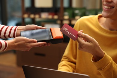 Photo of Man paying with credit card via terminal in cafe, closeup