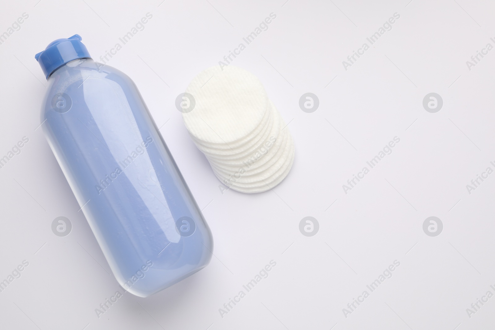 Photo of Clean cotton pads and micellar water on white background, top view. Space for text