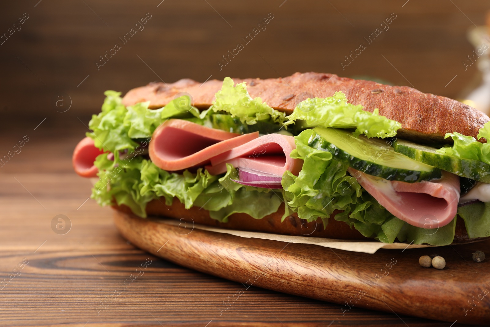 Photo of Delicious baguette sandwich with ham on wooden table, closeup