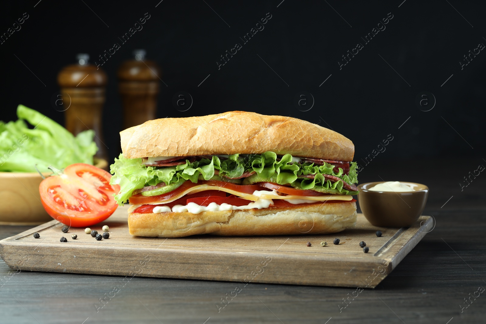 Photo of Delicious baguette sandwich with salami and cheese on grey wooden table