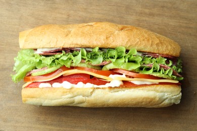 Photo of Delicious baguette sandwich with salami and cheese on wooden table, top view