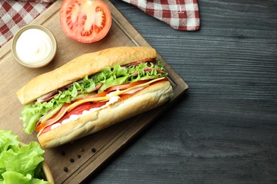 Photo of Delicious baguette sandwich with salami and cheese on grey wooden table, flat lay. Space for text