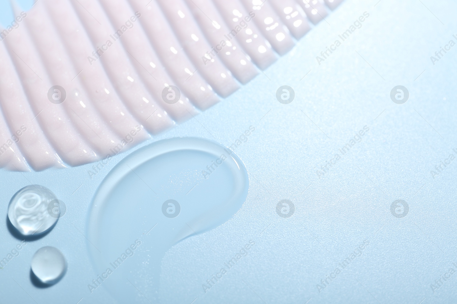 Photo of Cream and gel samples on light blue background, top view. Space for text