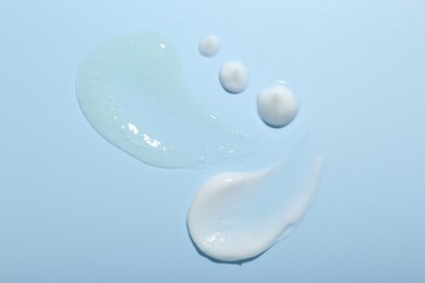 Photo of Cream and gel samples on light blue background, top view