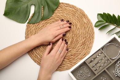 Photo of Woman wearing beautiful rings at white table, top view