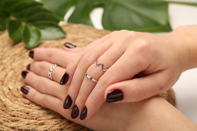 Photo of Woman wearing beautiful rings at white table, closeup