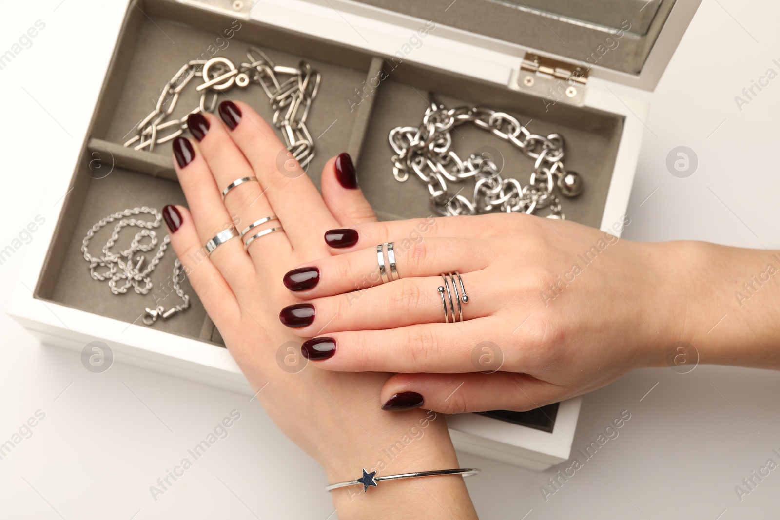 Photo of Woman wearing beautiful rings and jewelry box with different accessories on white background, closeup