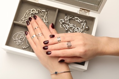 Photo of Woman wearing beautiful rings and jewelry box with different accessories on white background, closeup