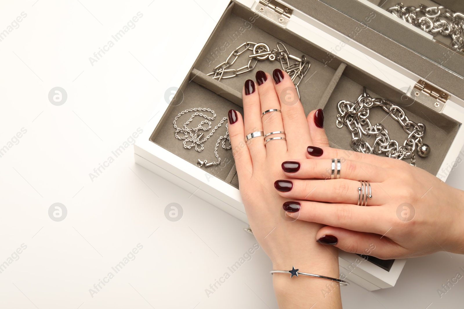 Photo of Woman wearing beautiful rings and jewelry box with different accessories on white background, closeup. Space for text