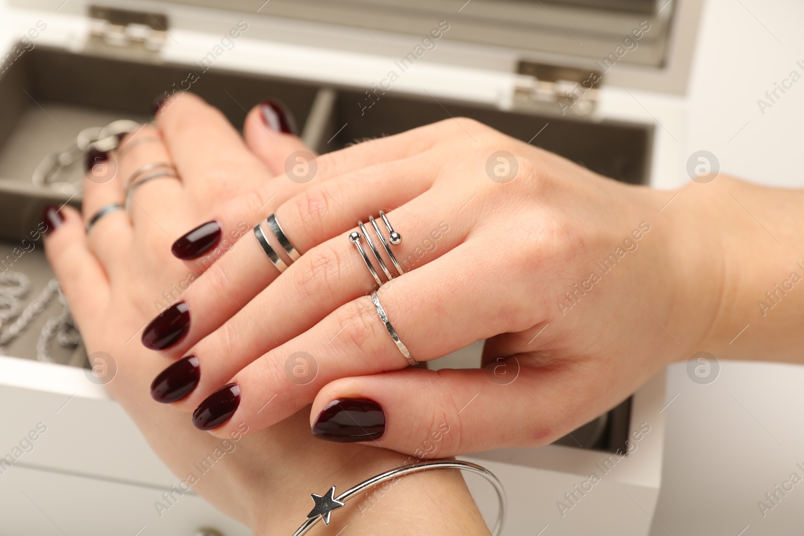 Photo of Woman wearing beautiful rings and jewelry box with different accessories on white background, closeup