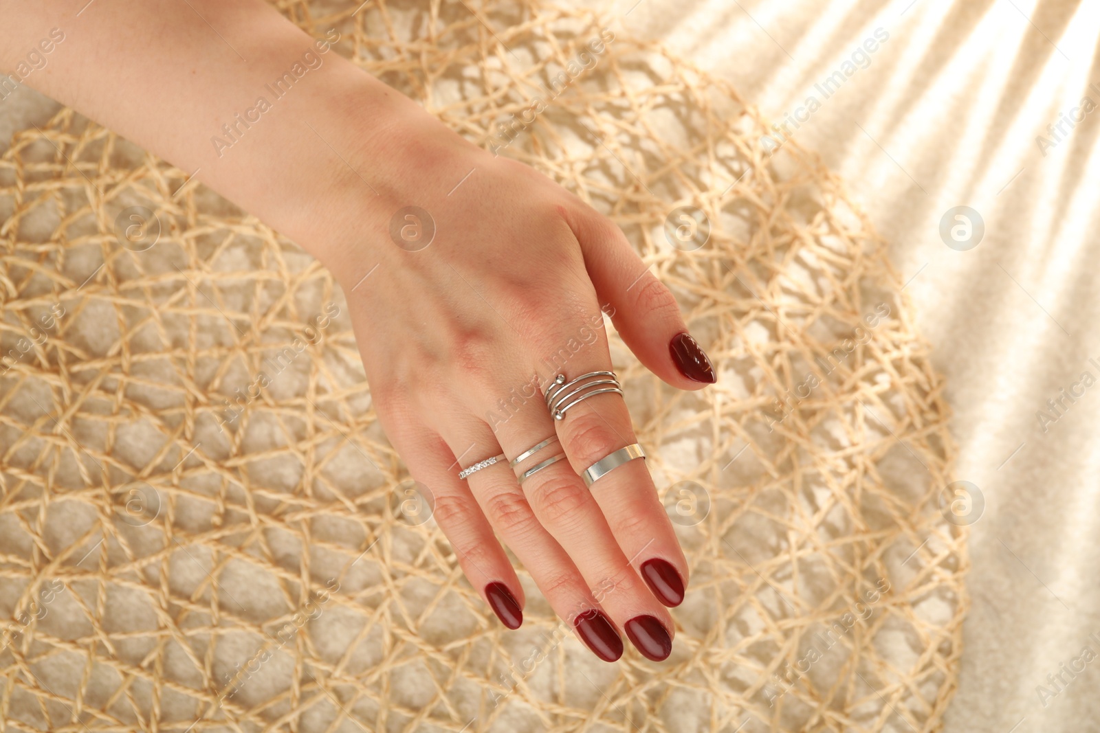 Photo of Woman wearing beautiful rings on beige background, closeup