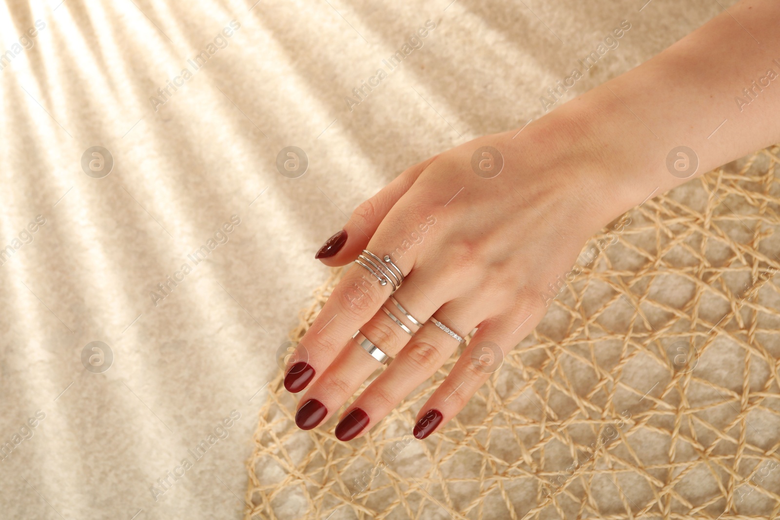 Photo of Woman wearing beautiful rings on beige background, closeup. Space for text