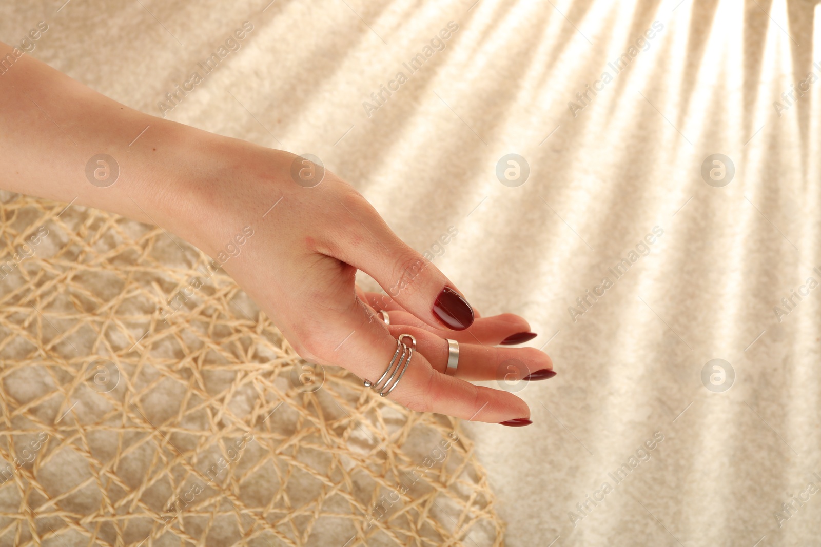 Photo of Woman wearing beautiful rings on beige background, closeup. Space for text