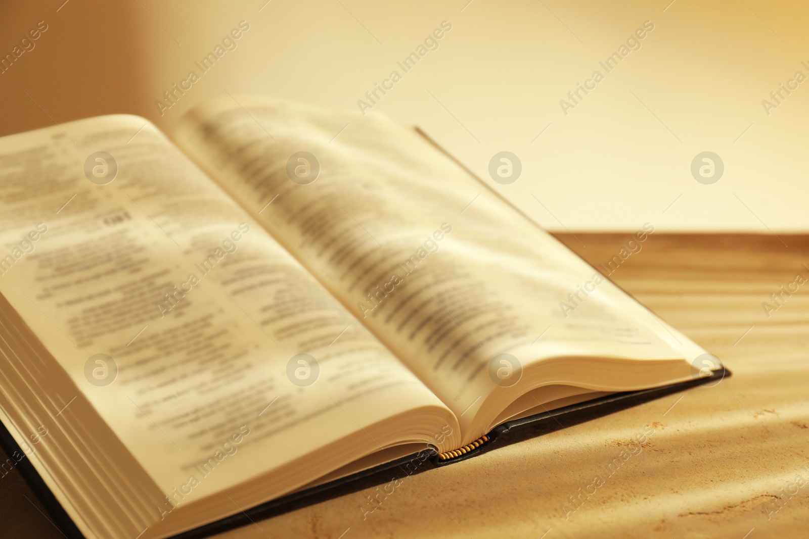 Photo of Open Holy Bible on beige table, closeup