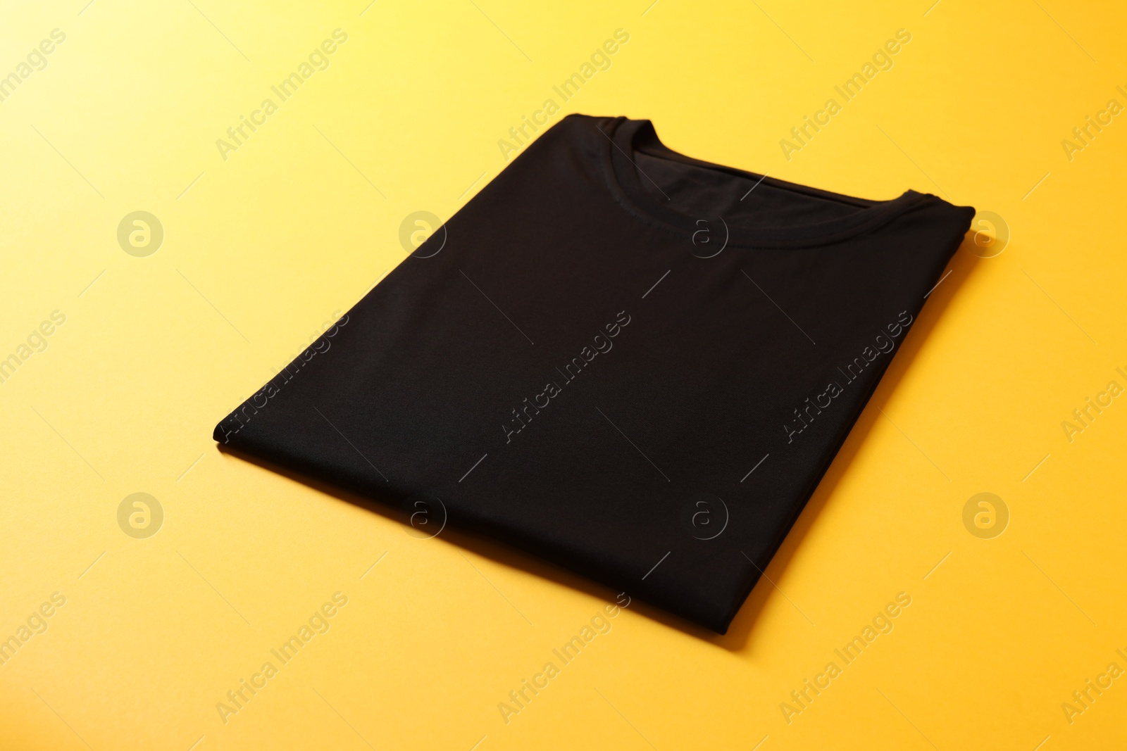 Photo of Blank black t-shirt on yellow background. Mockup for design