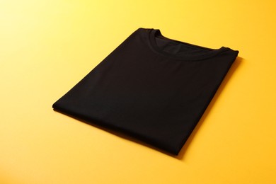 Photo of Blank black t-shirt on yellow background. Mockup for design