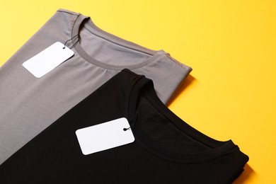 Photo of Different blank t-shirts on yellow background, closeup