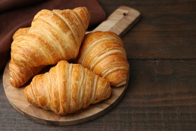 Photo of Tasty fresh croissants on wooden table, closeup. Space for text