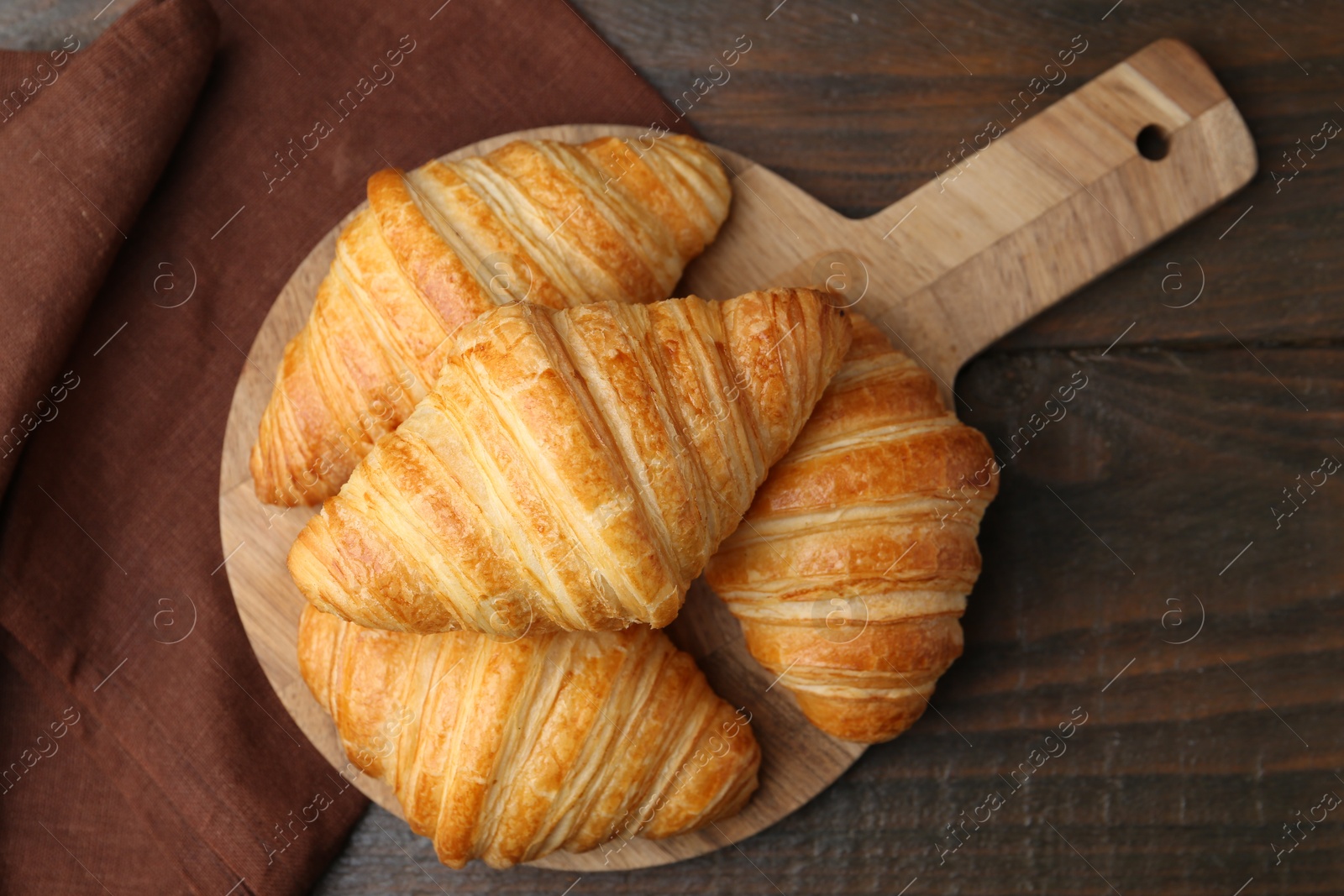 Photo of Tasty fresh croissants on wooden table, top view. Puff pastry