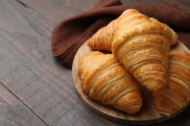 Photo of Tasty fresh croissants on wooden table, closeup. Space for text