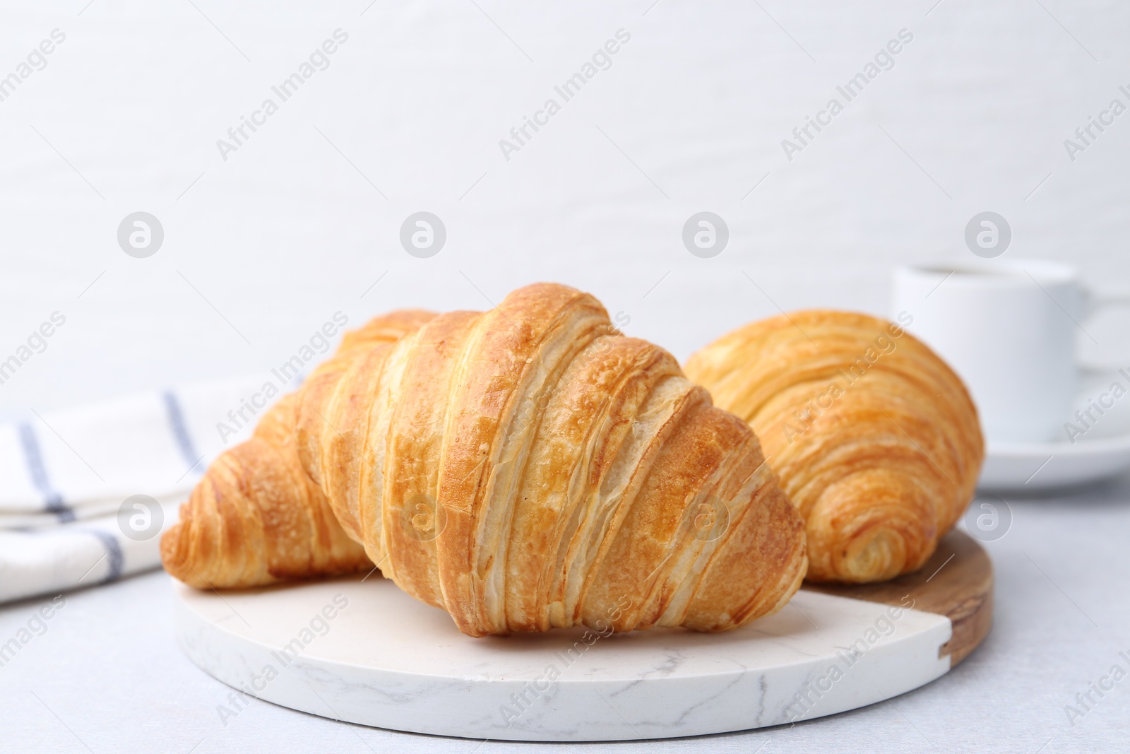 Photo of Tasty fresh croissants on light table, closeup