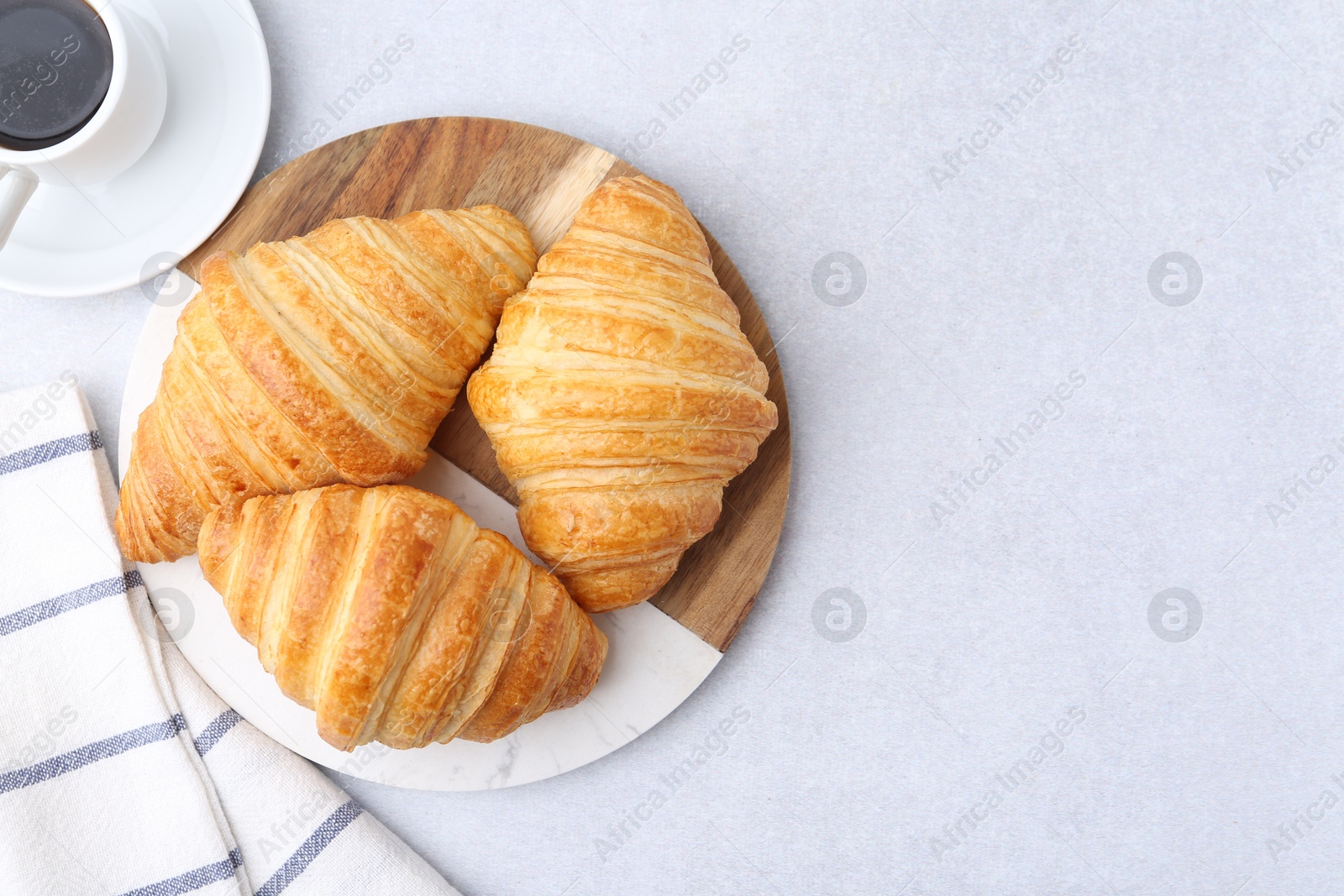 Photo of Tasty fresh croissants and cup of coffee on light grey table, flat lay. Space for text