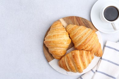 Photo of Tasty fresh croissants and cup of coffee on light grey table, flat lay. Space for text