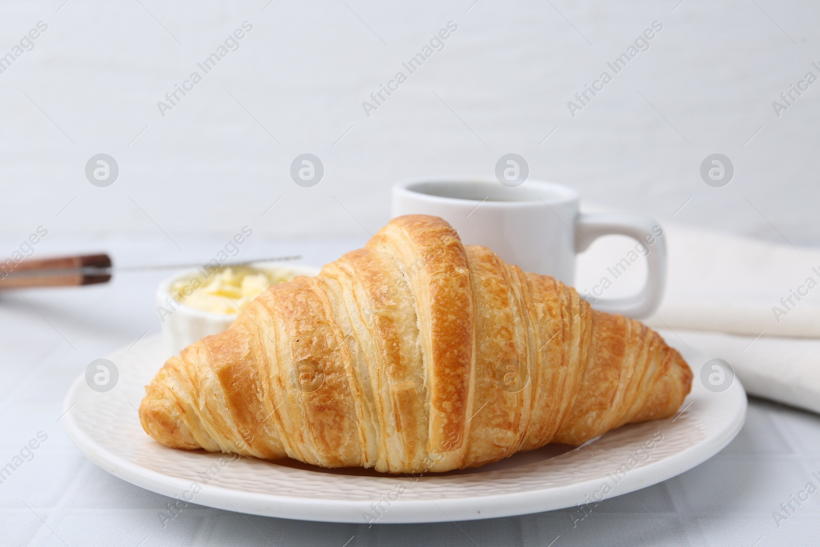 Photo of Tasty fresh croissant served on white tiled table, closeup