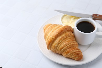 Photo of Tasty fresh croissant served with butter and cup of coffee on white tiled table, closeup. Space for text