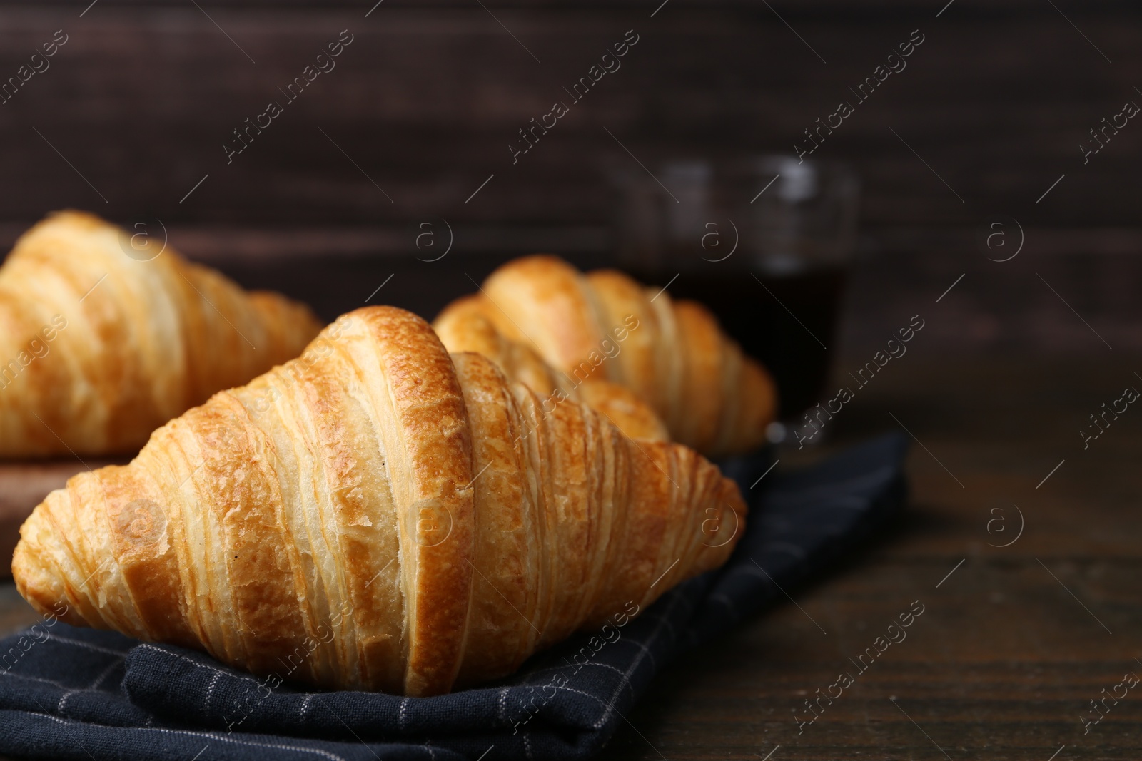 Photo of Tasty fresh croissants on wooden table, closeup. Space for text