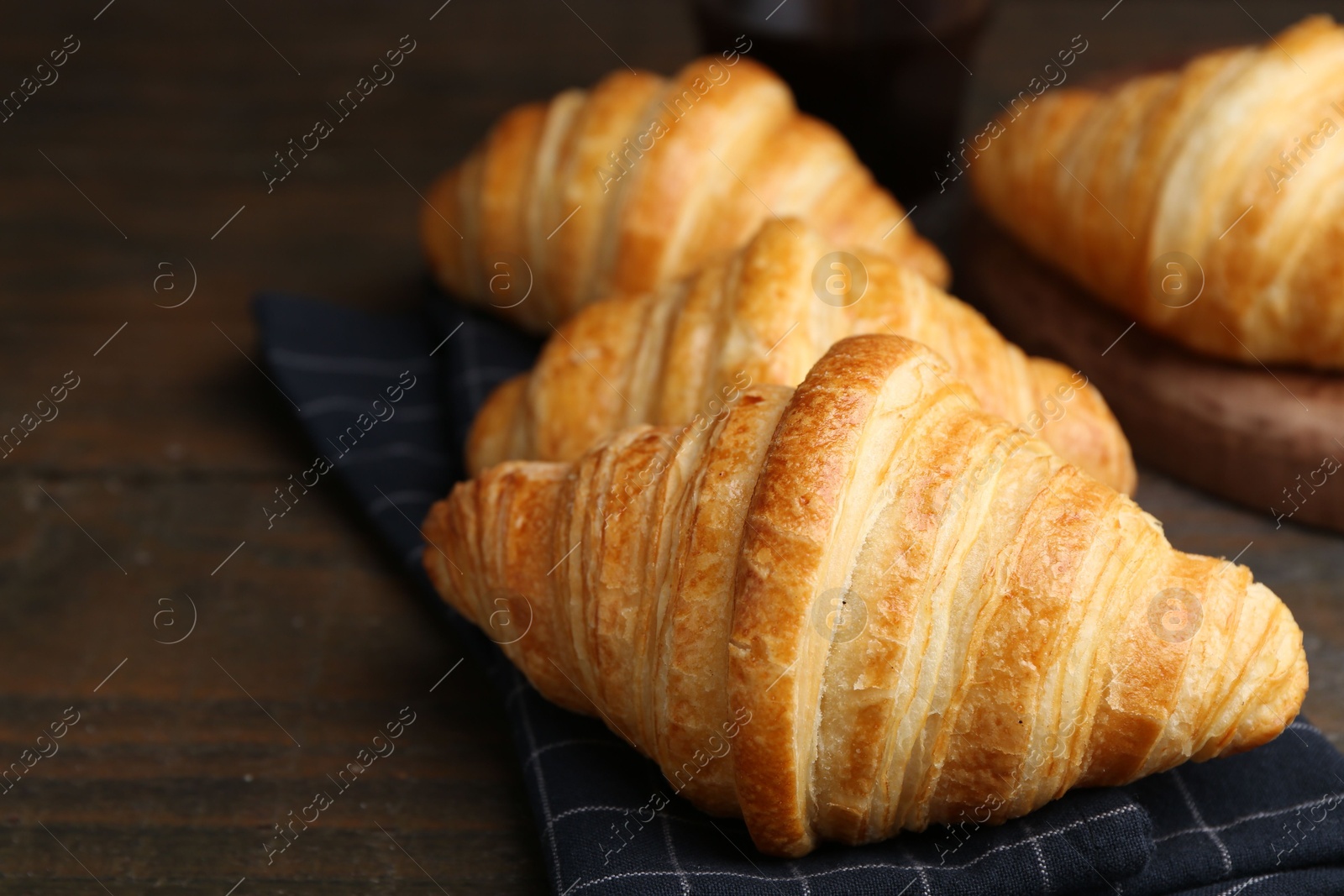 Photo of Tasty fresh croissants on wooden table, closeup. Puff pastry