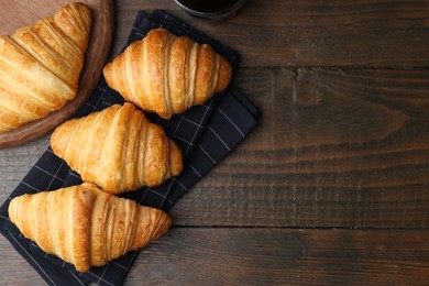 Photo of Tasty fresh croissants on wooden table, flat lay. Space for text