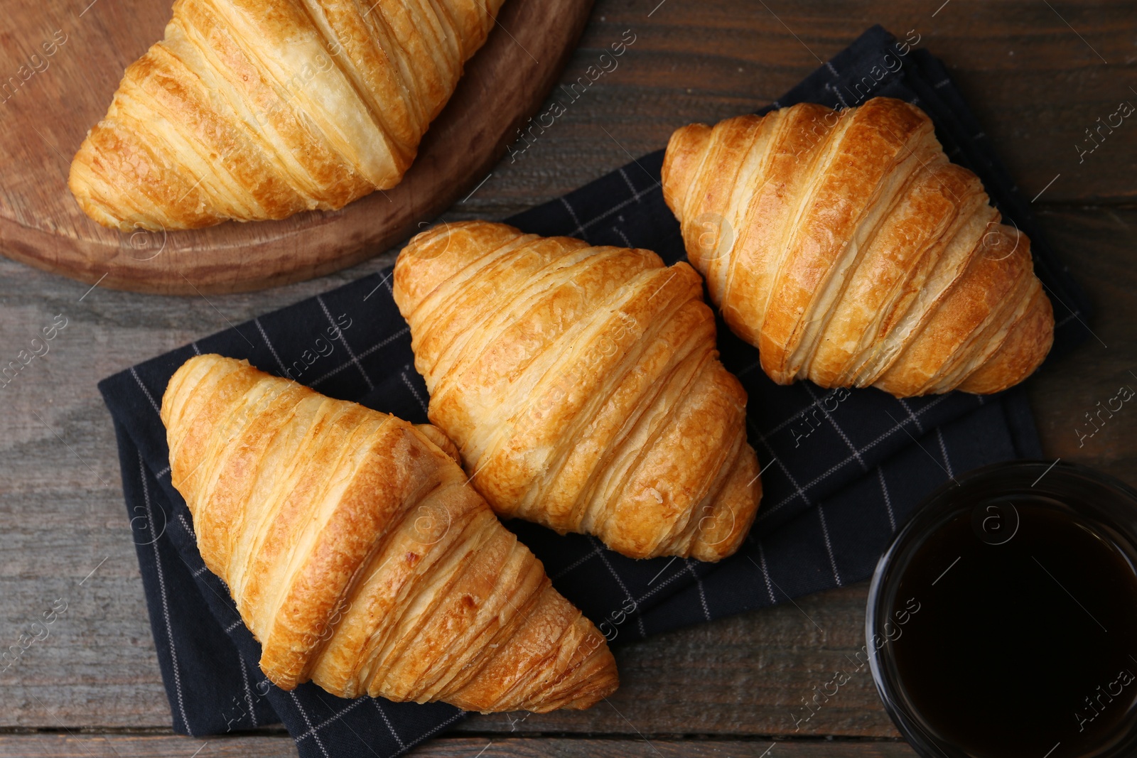 Photo of Tasty fresh croissants and drink on wooden table, flat lay