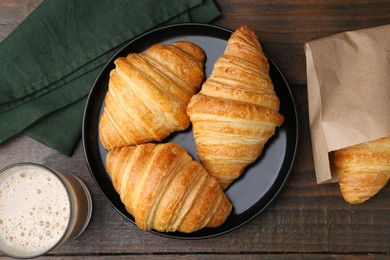 Photo of Tasty fresh croissants and drink on wooden table, flat lay