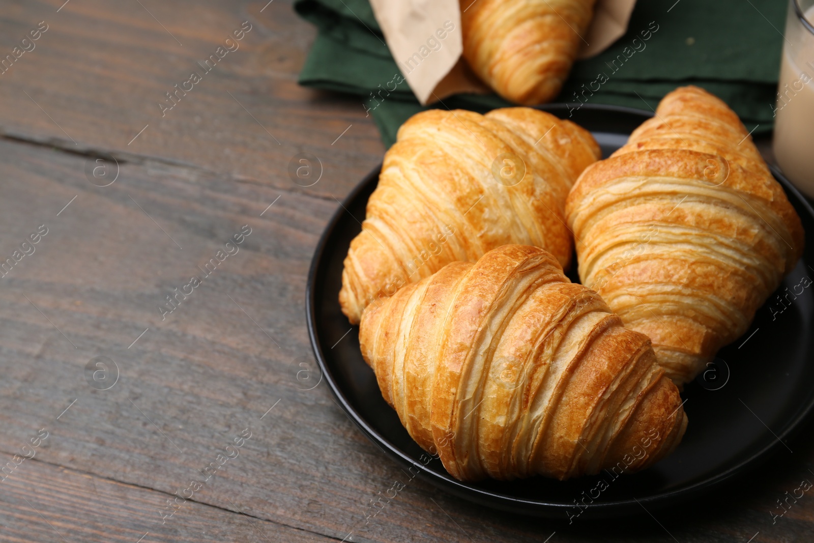 Photo of Tasty fresh croissants on wooden table, closeup. Space for text