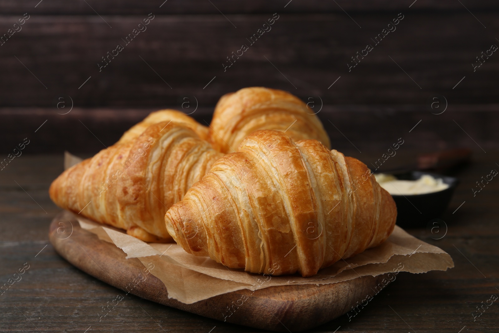 Photo of Tasty fresh croissants on wooden table, closeup