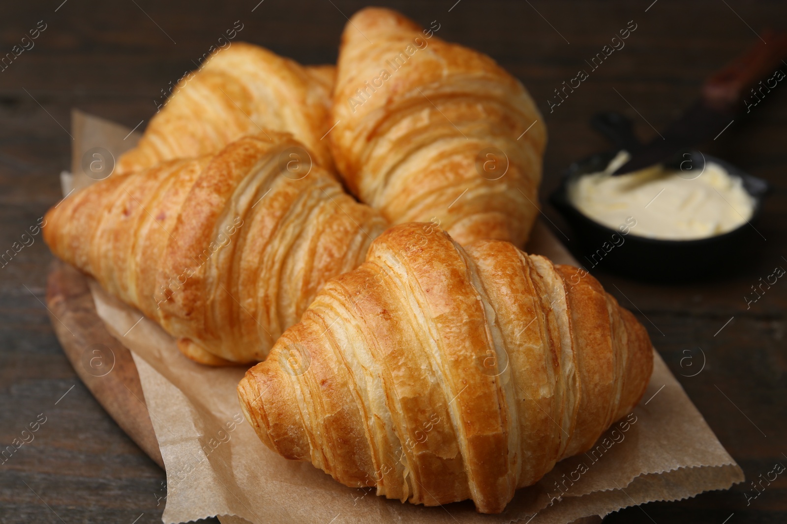 Photo of Tasty fresh croissants served with butter on wooden table, closeup