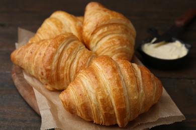 Photo of Tasty fresh croissants served with butter on wooden table, closeup