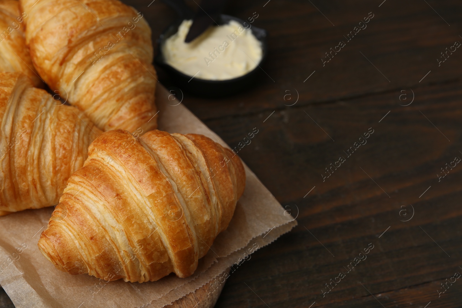 Photo of Tasty fresh croissants served with butter on wooden table, closeup. Space for text