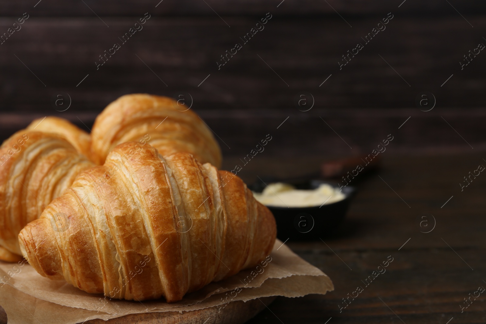 Photo of Tasty fresh croissants on wooden table, closeup. Space for text