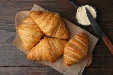 Photo of Tasty fresh croissants served with butter on wooden table, flat lay