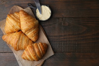 Photo of Tasty fresh croissants served with butter on wooden table, flat lay. Space for text