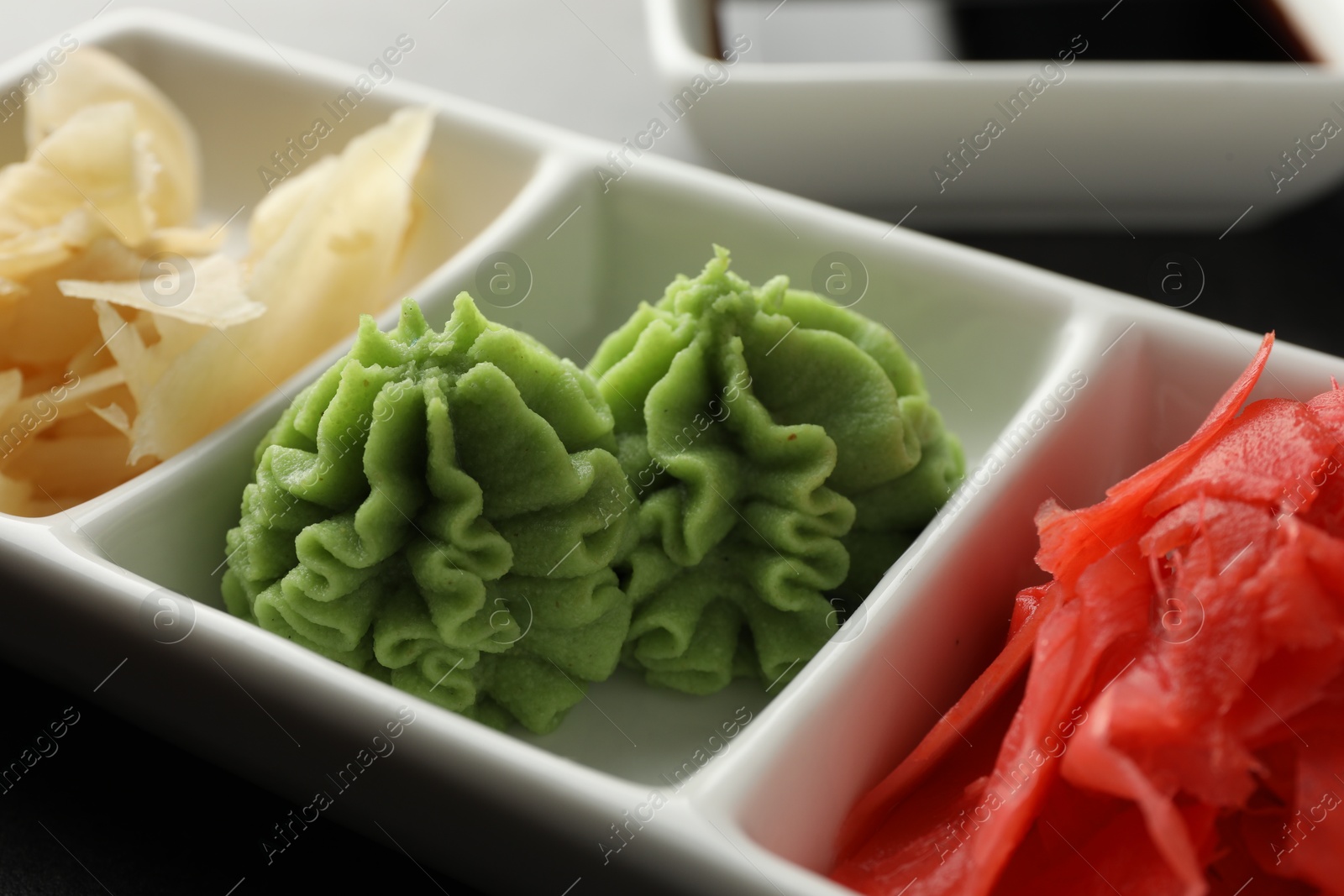 Photo of Hot wasabi paste and ginger on grey table, closeup