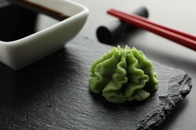 Photo of Hot wasabi paste, soy sauce and chopsticks on grey table, closeup