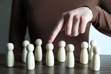 Photo of Human resources concept. Woman pointing at wooden piece among other ones at table, closeup