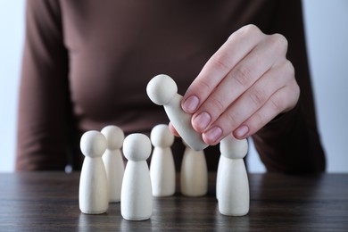 Photo of Human resources concept. Woman choosing wooden piece between other ones at table, closeup