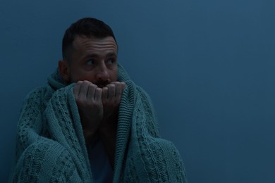 Photo of Fear of darkness. Scared man with blanket on light grey background, space for text