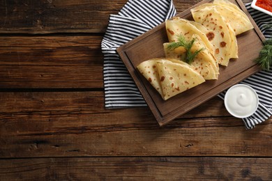 Photo of Delicious crepes, dill and sour cream on wooden table, flat lay. Space for text