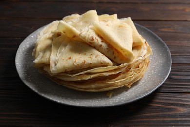 Photo of Tasty crepes on wooden table, closeup view